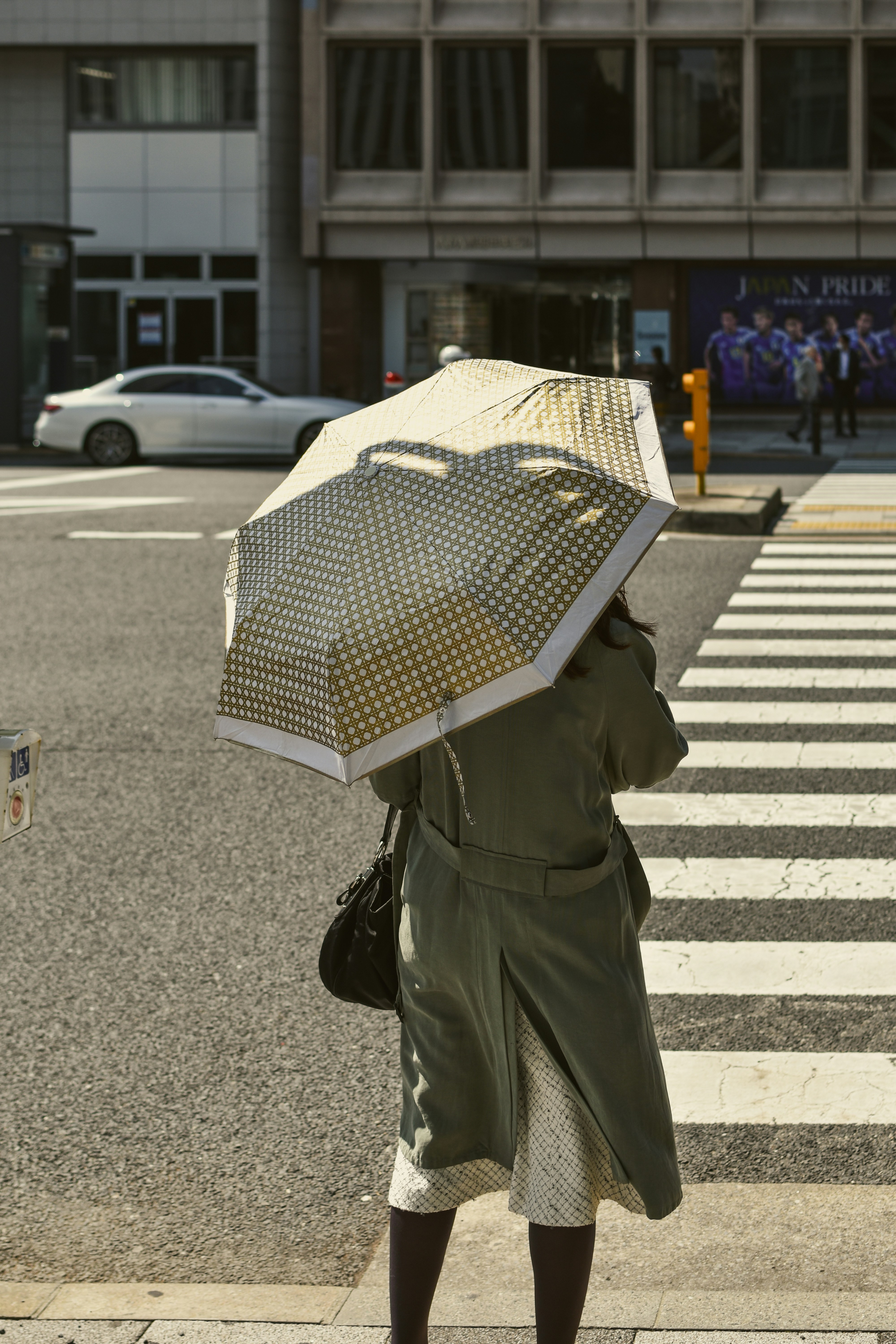 A person holds an umbrella while crossing a street.