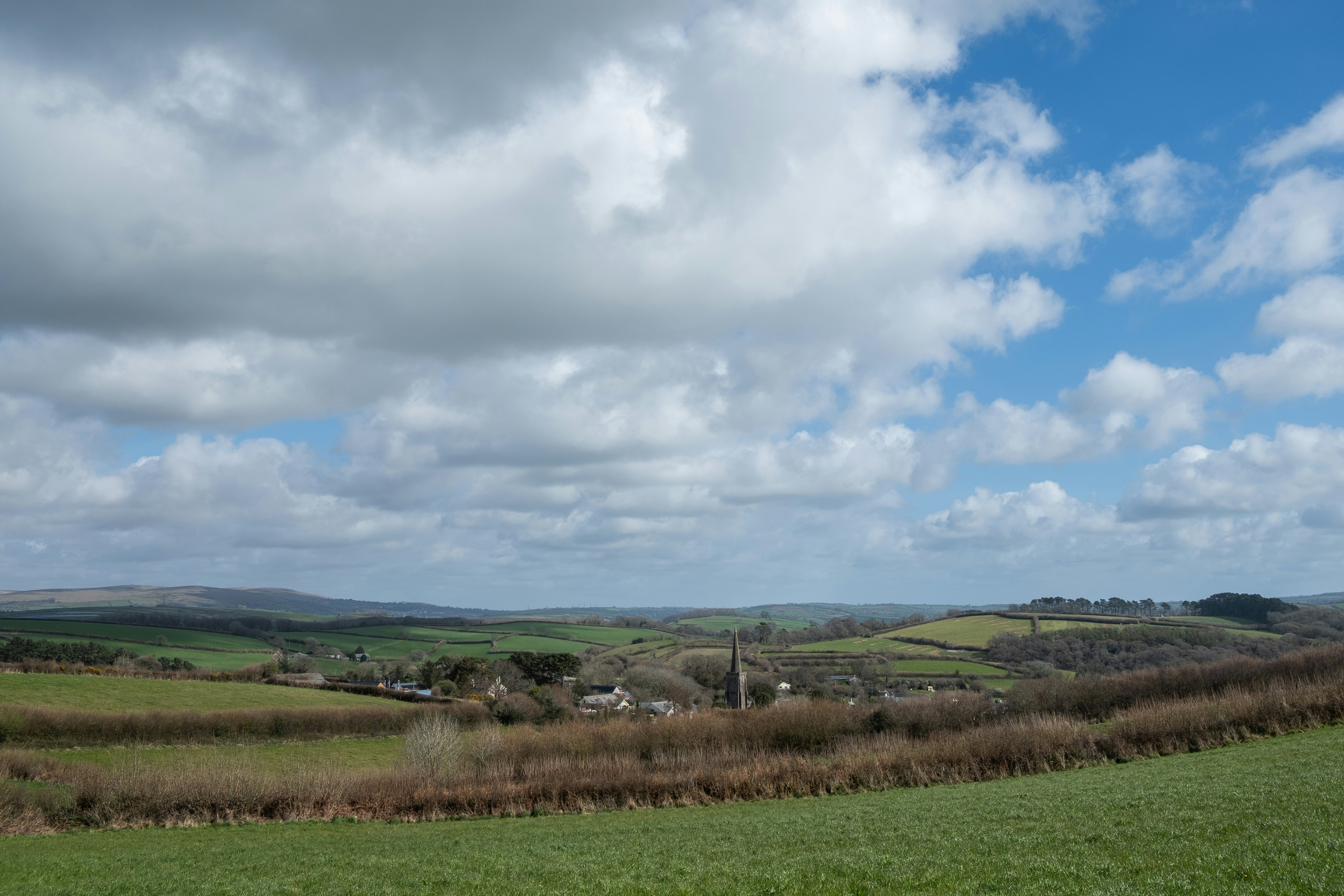 Rolling green hills and a cloudy, blue sky., Rural village in south Devon