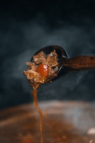 Steaming stew drips from a wooden spoon.