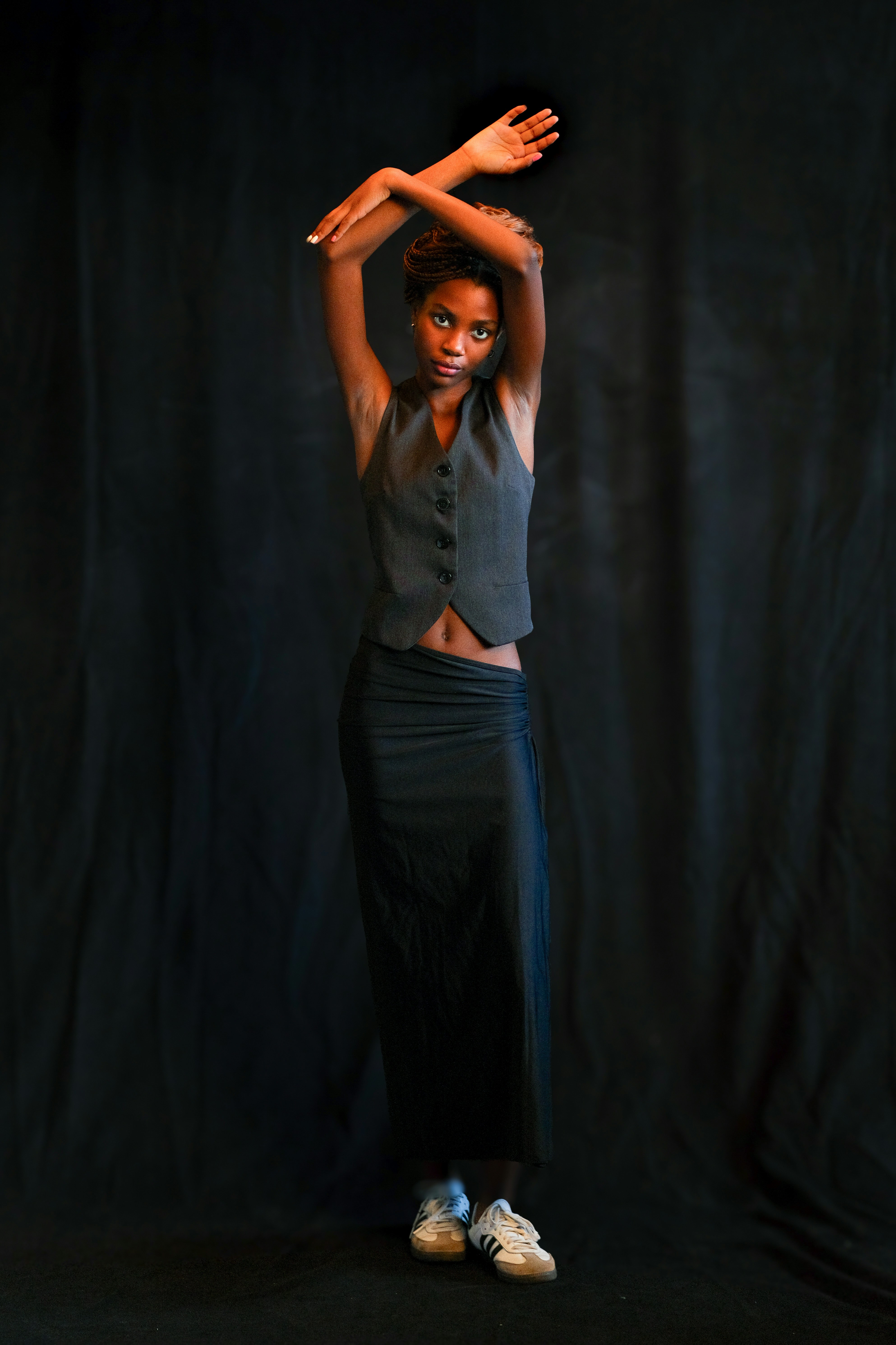 A woman poses with arms crossed above her head.