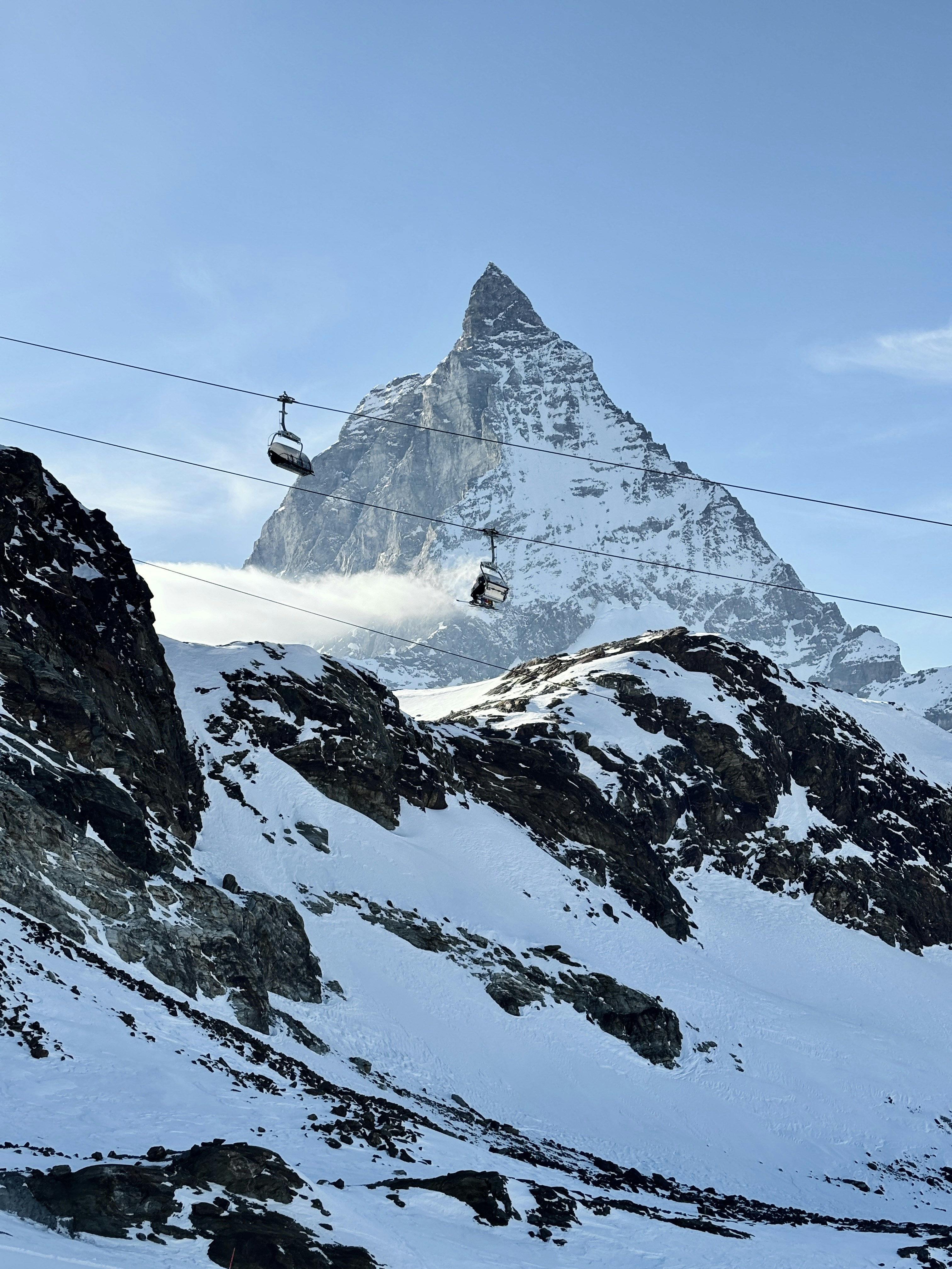 Cable cars ascend near the snow-covered matterhorn.