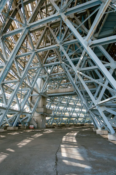 A complex blue steel truss structure forming a large industrial interior space