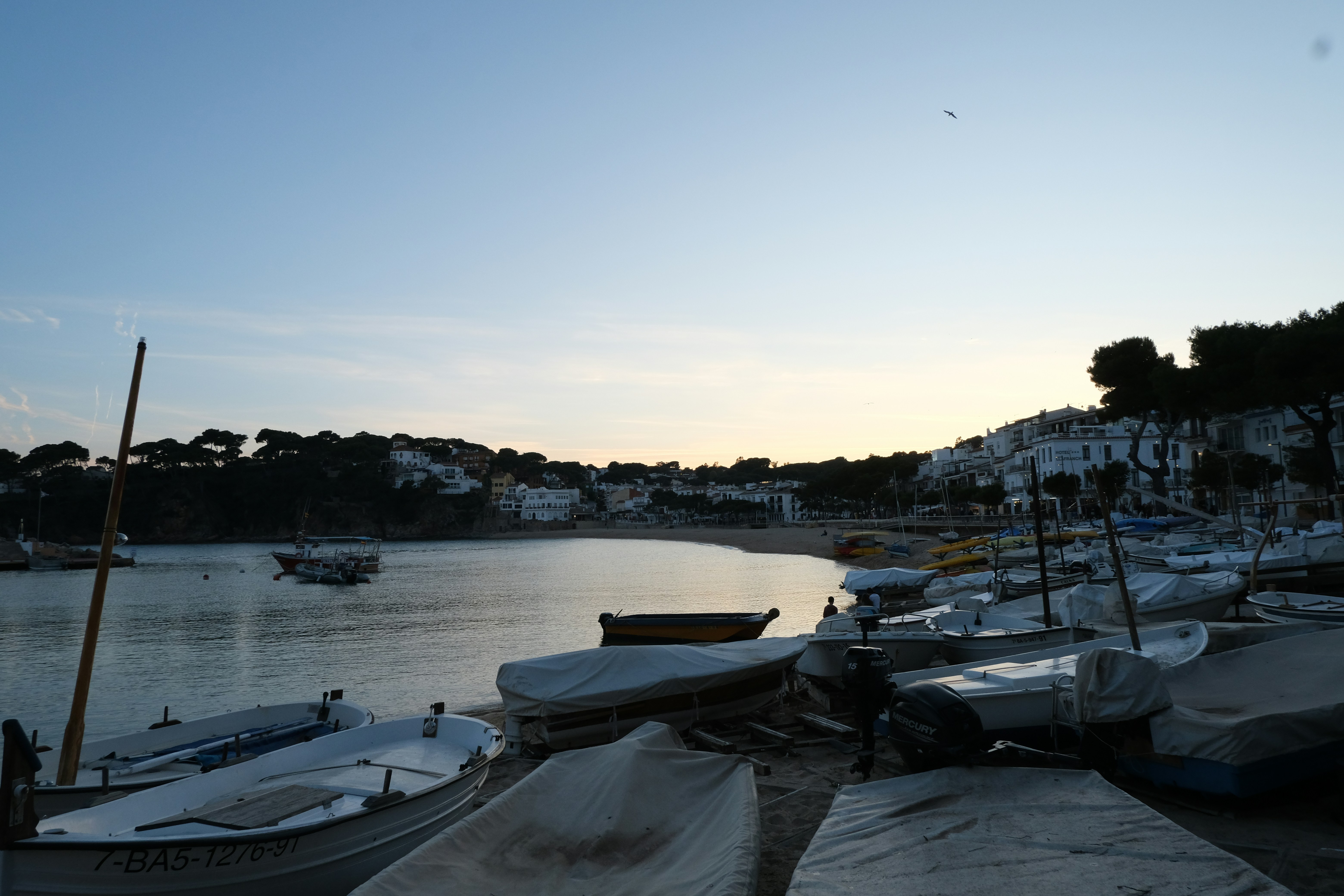Boats sit on shore at a calm, dusky bay.
