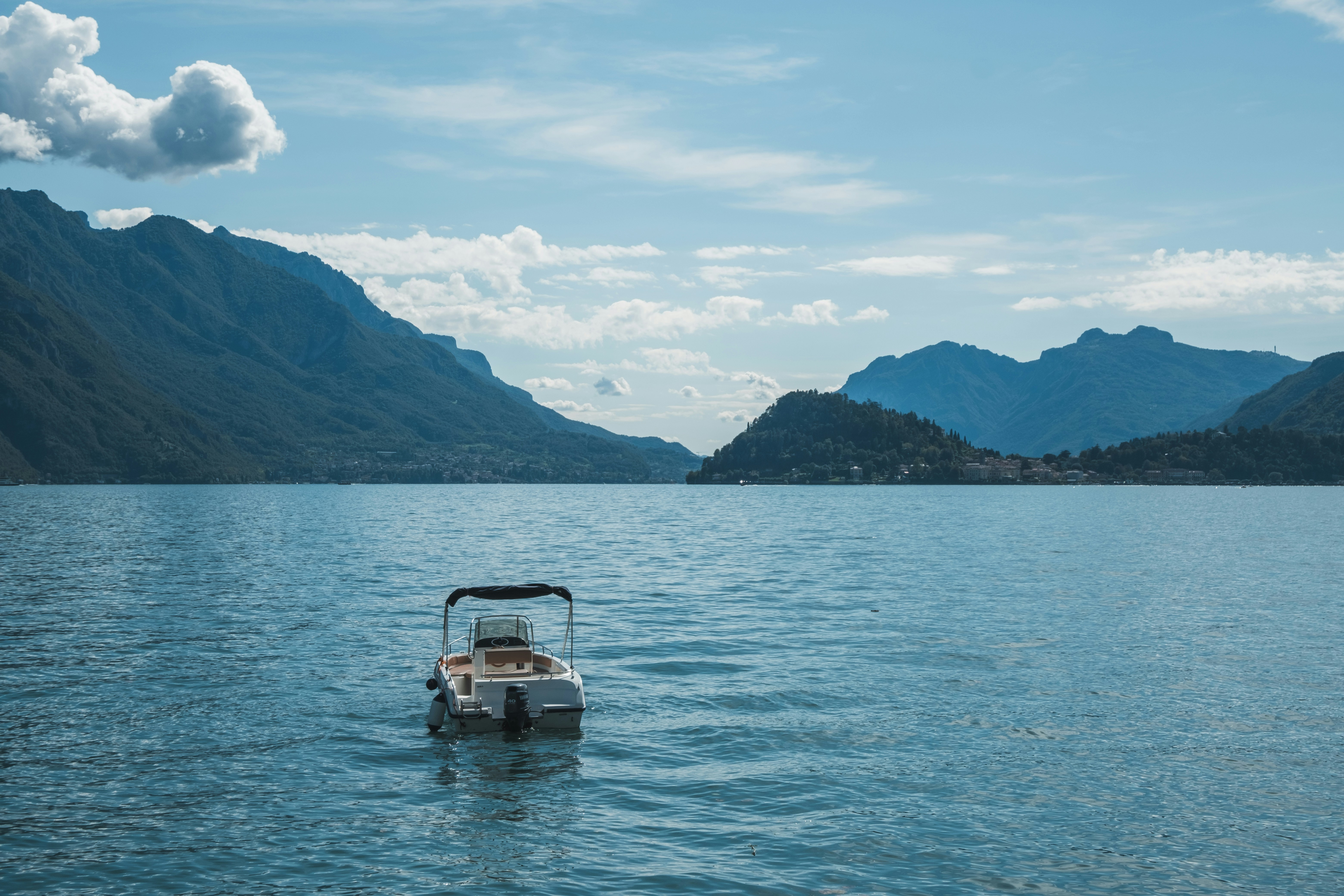 Boat floats on lake, mountains in the background.