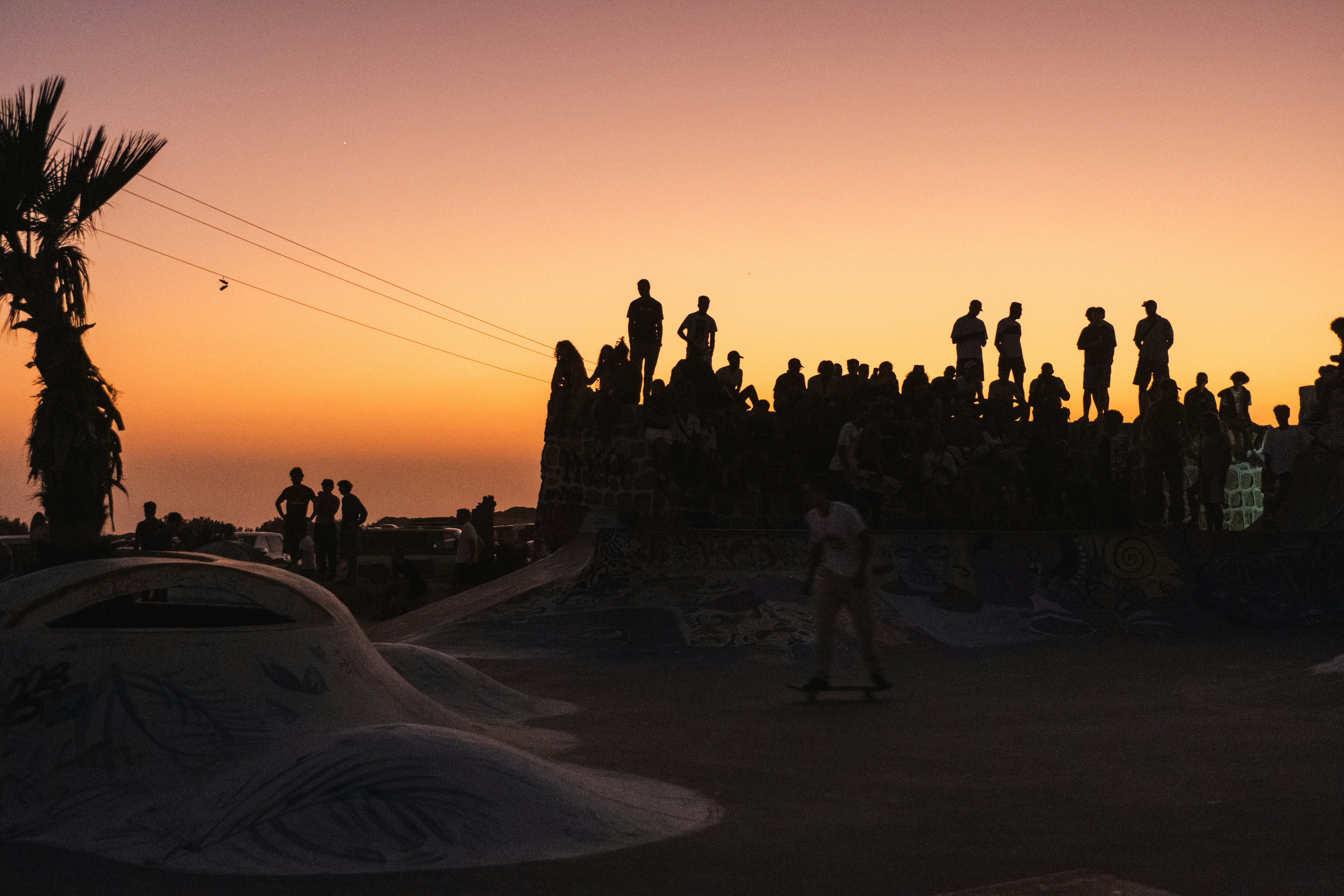 Silhouettes of people gather during sunset.