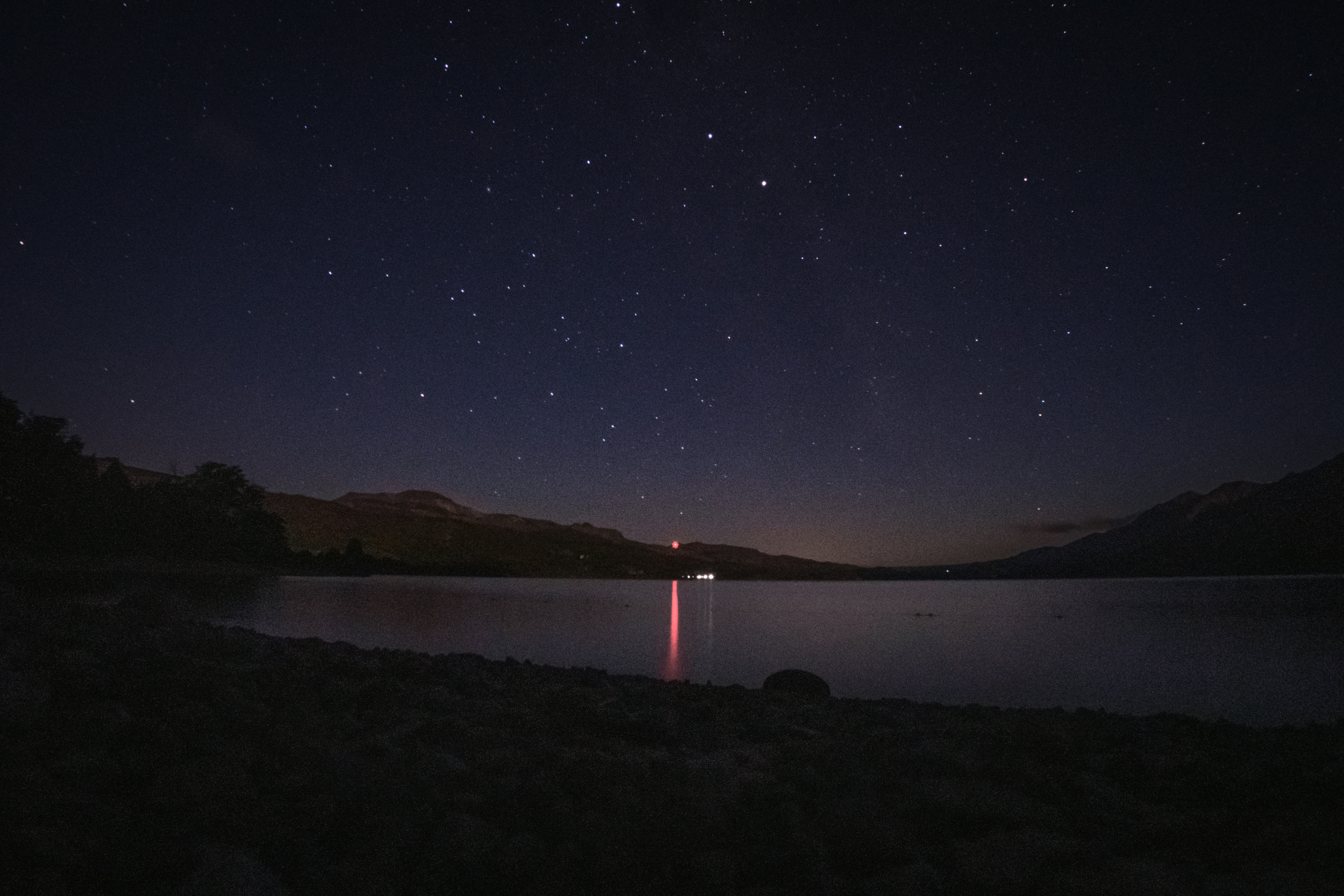 Stars shimmer over a calm lake at night.