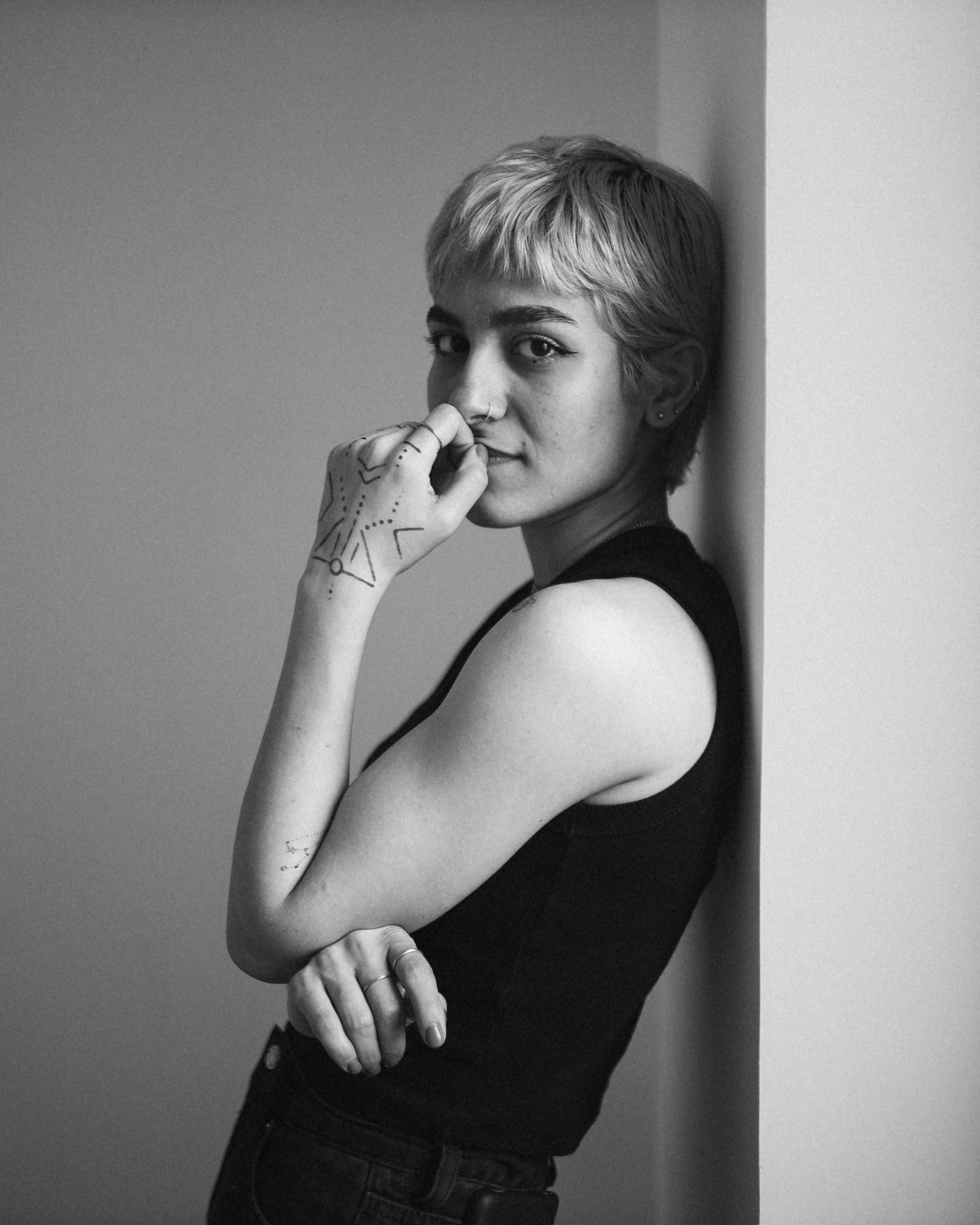 A woman leans against a wall and poses.