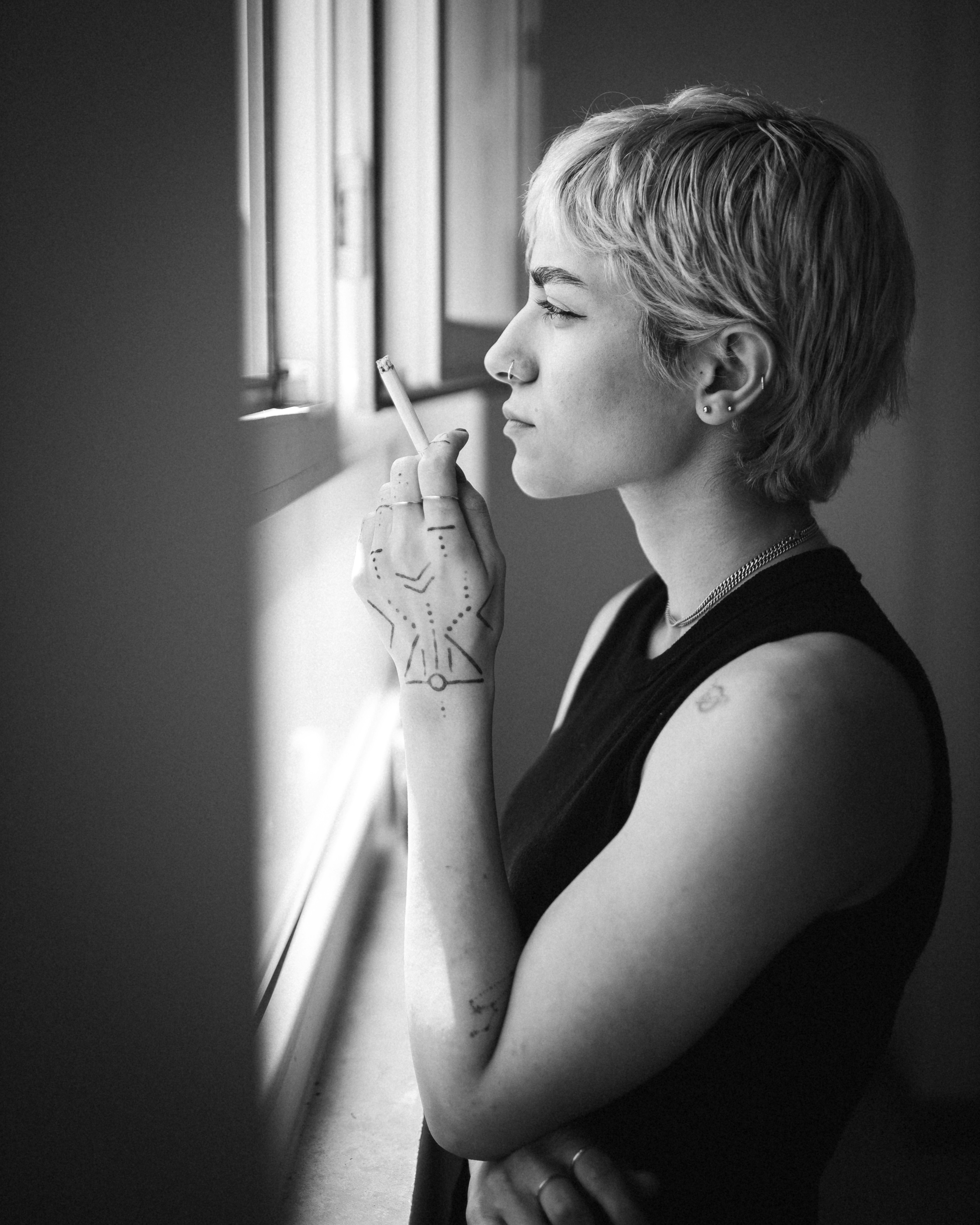 窓辺でタバコを吸う女性。