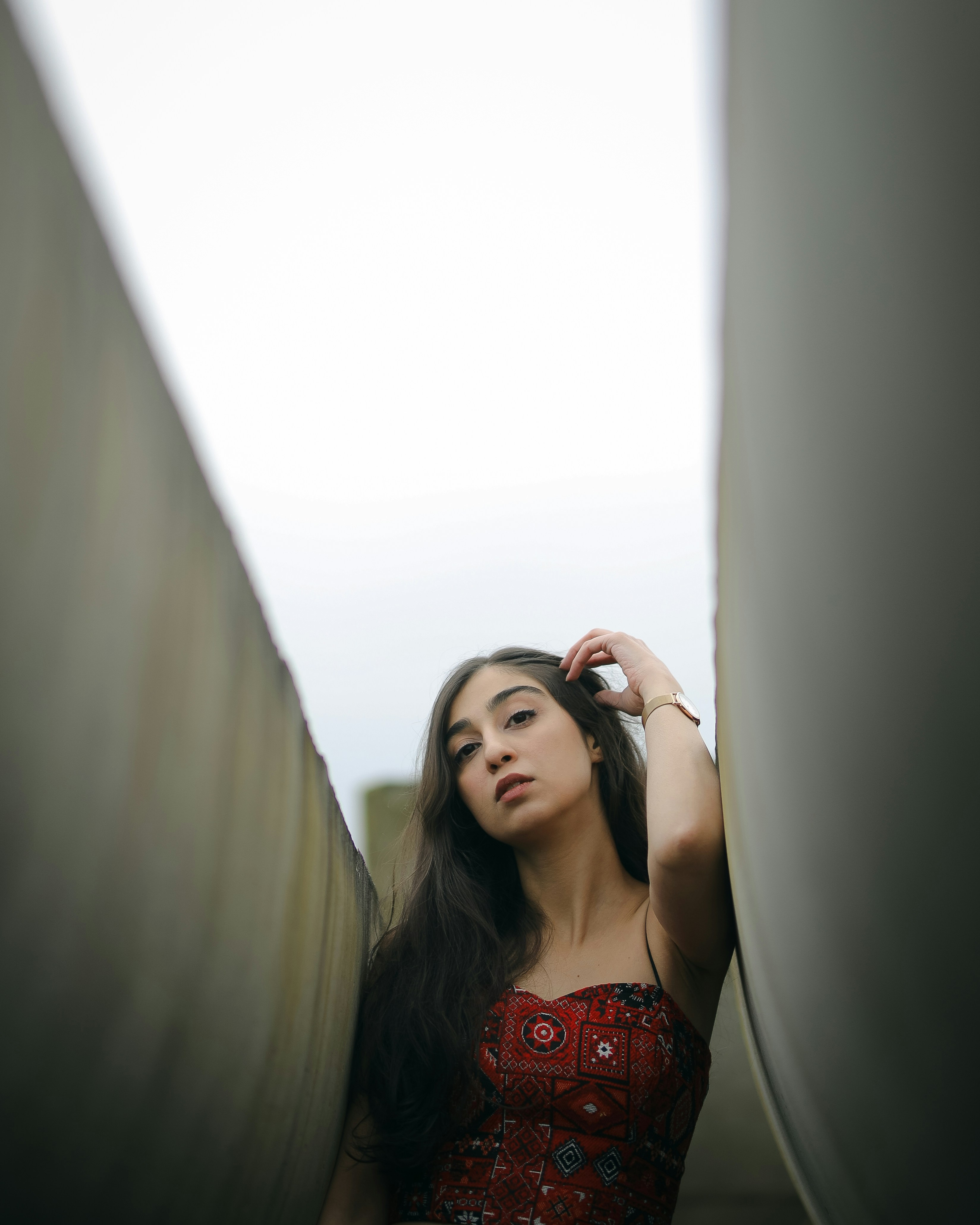 A woman poses between two grey walls.