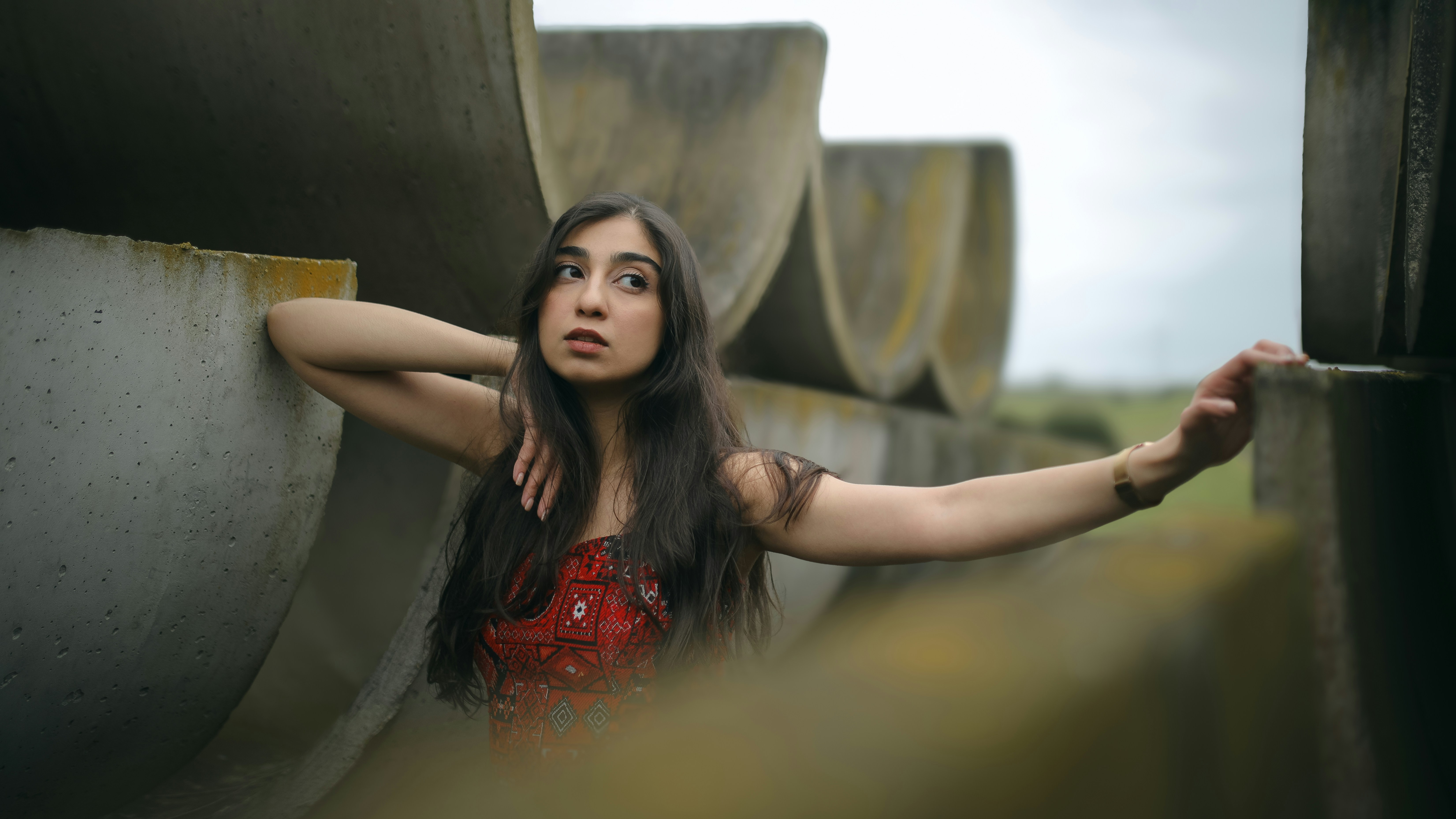 屋外の大きなコンクリートパイプの近くでポーズをとる女性。