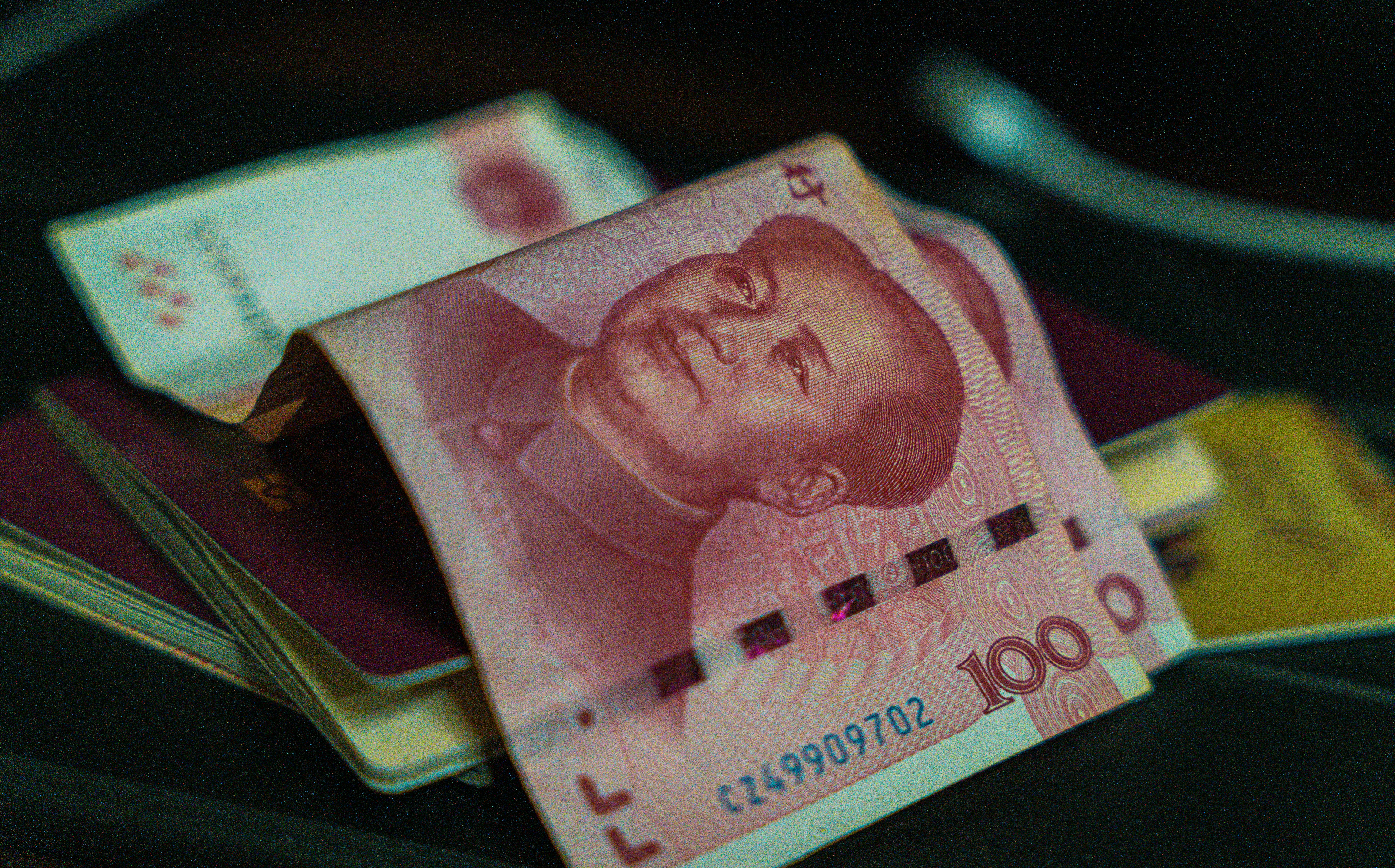 One hundred chinese yuan sits on top of passports.