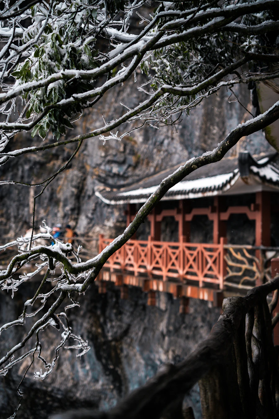 Traditional Chinese temple pavilion adorned with snowy winter branches and rime ice on Tianmen Mountain summit