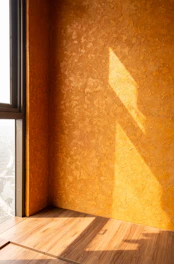 Sunlight casts shadows on an orange textured wall