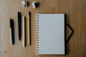 Notebook and writing supplies on wooden surface.