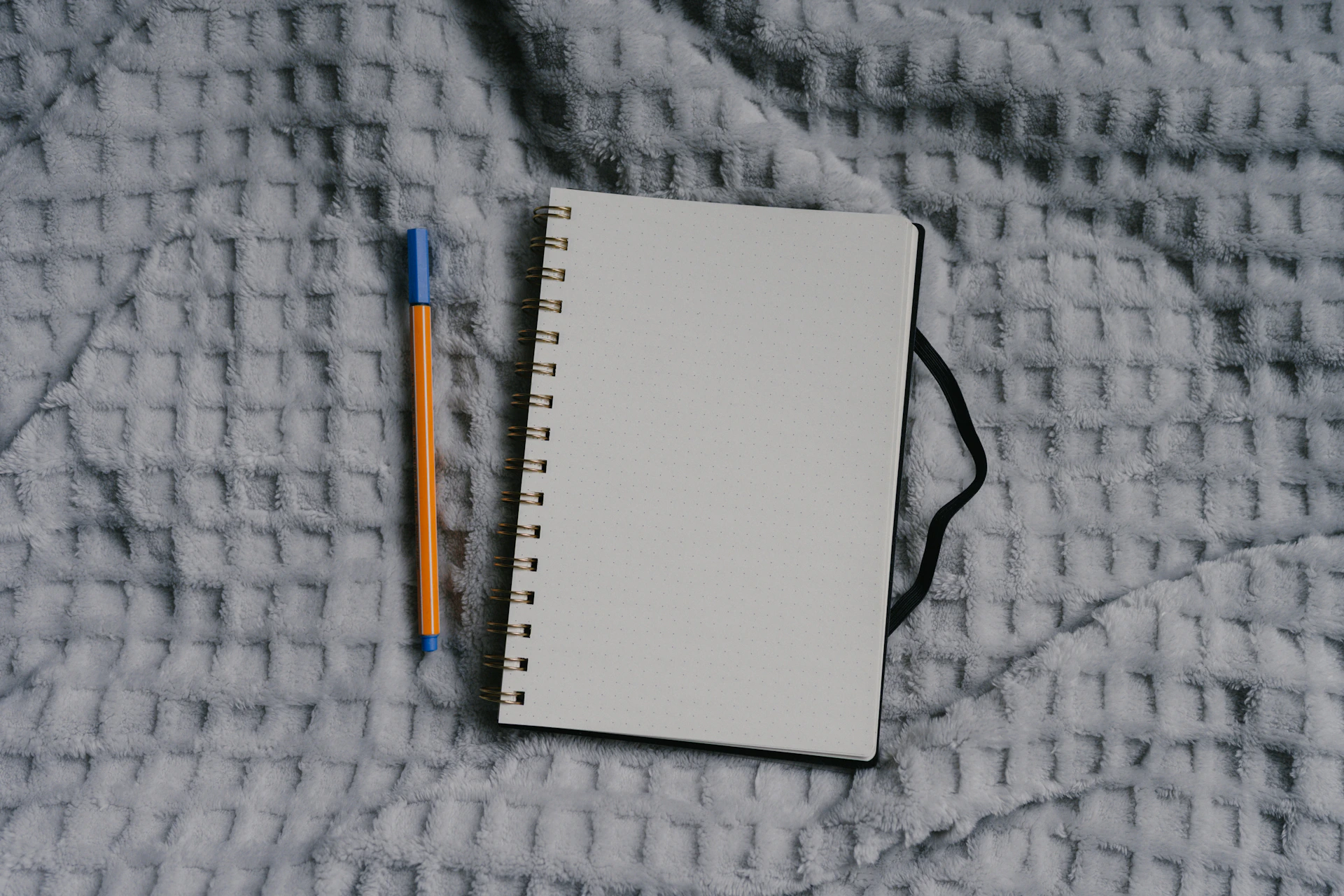 Notebook and pen sit on a textured surface