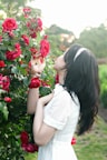 A woman admires the fragrant red roses.