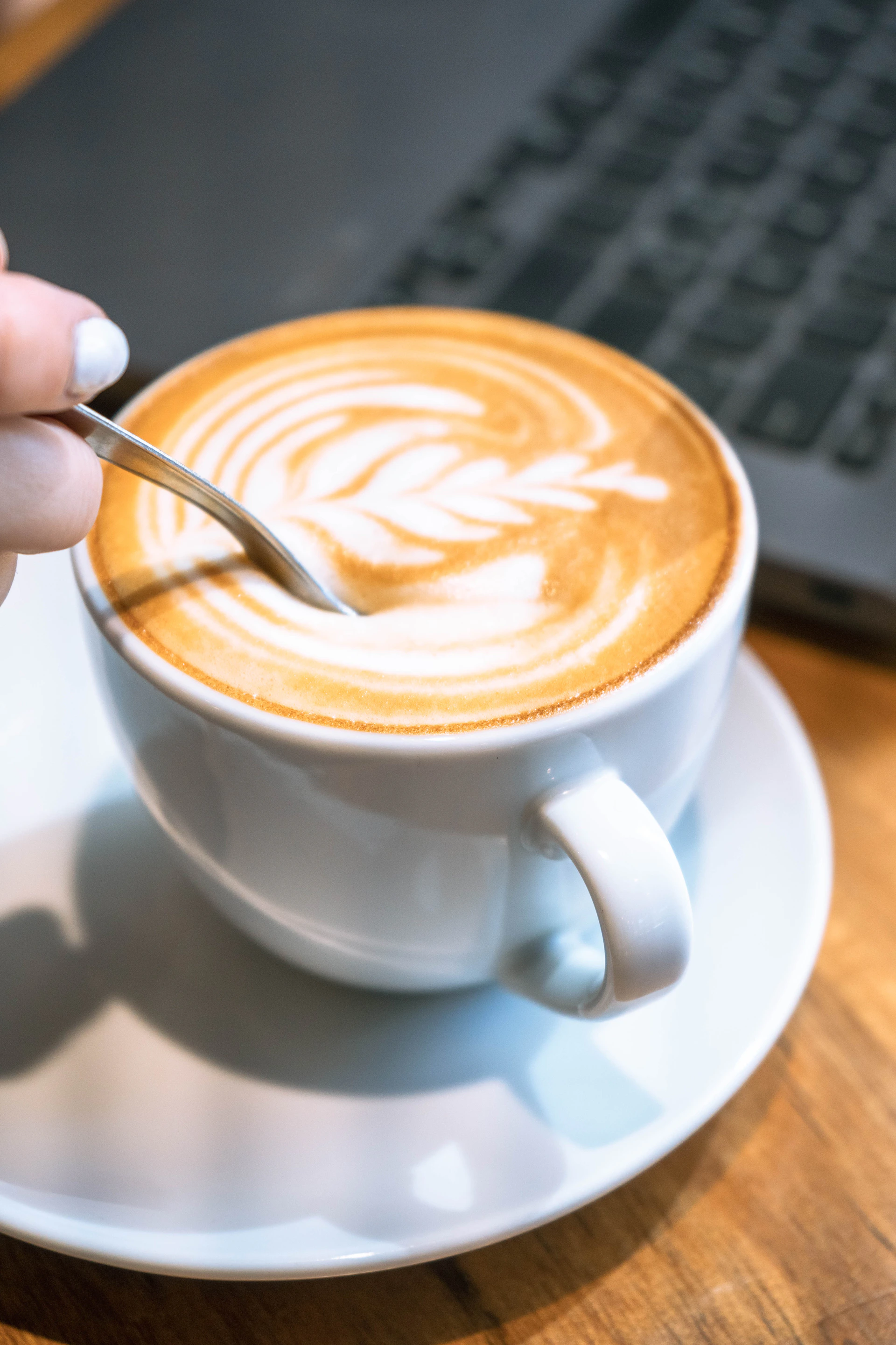Stirring a cup of coffee with latte art.