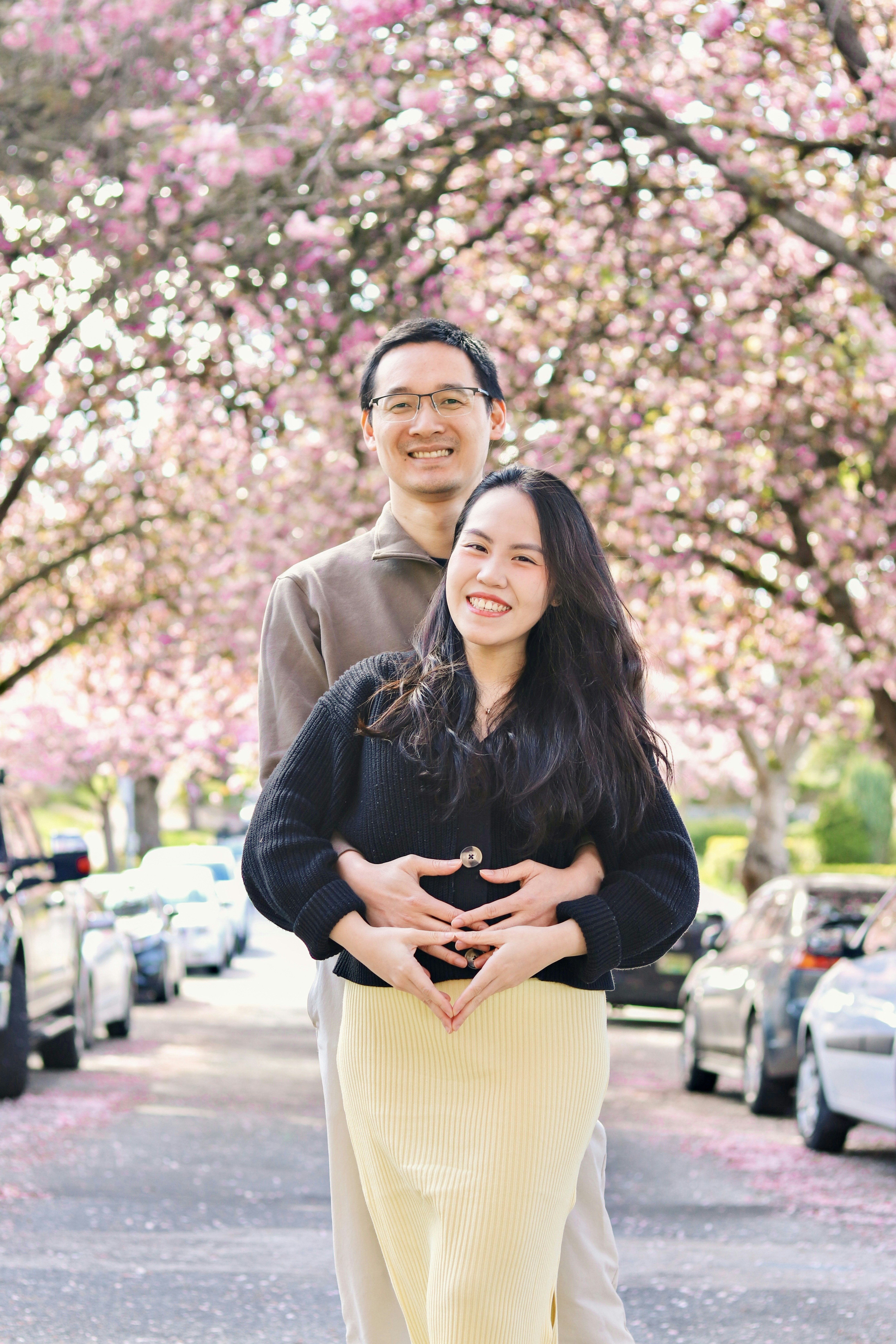 Ein Paar posiert unter Kirschblüten.