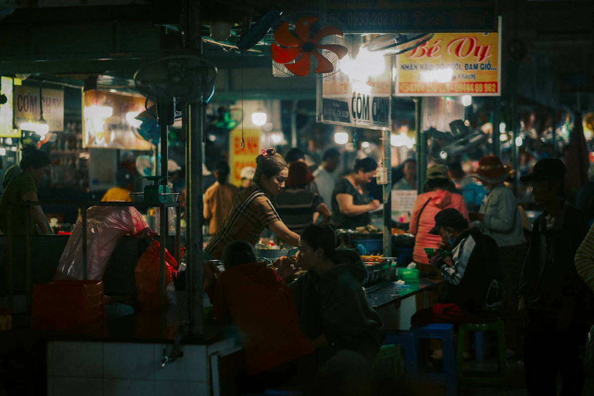 People eating at night street food stalls under hanging lamps in Kuala Lumpur