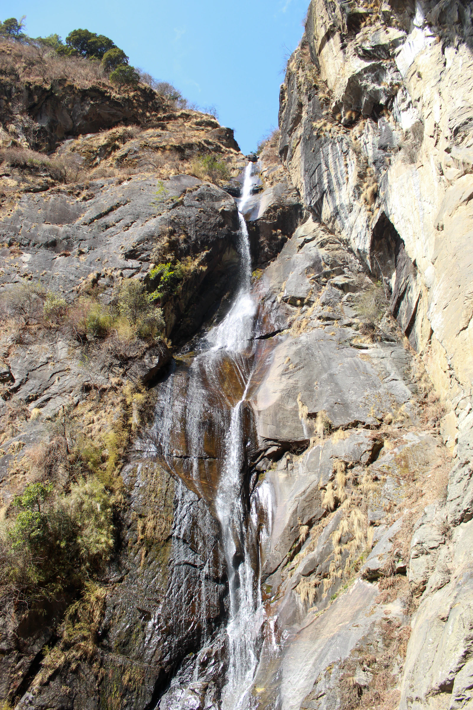 The waterfall below Taktsang falling in a long white thread down bare granite beside the trail to the monastery