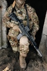 A soldier in combat gear holds a rifle.