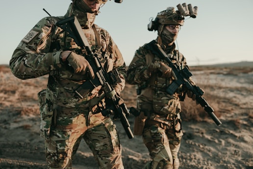Soldiers walk through a desert landscape.