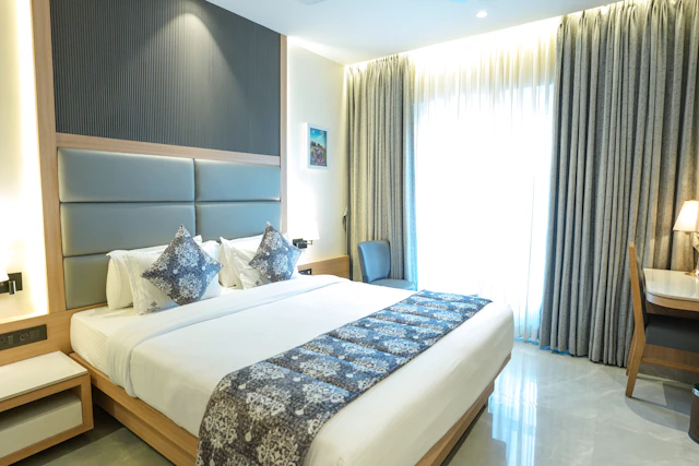 Hotel bedroom with white bedding and a blue upholstered headboard