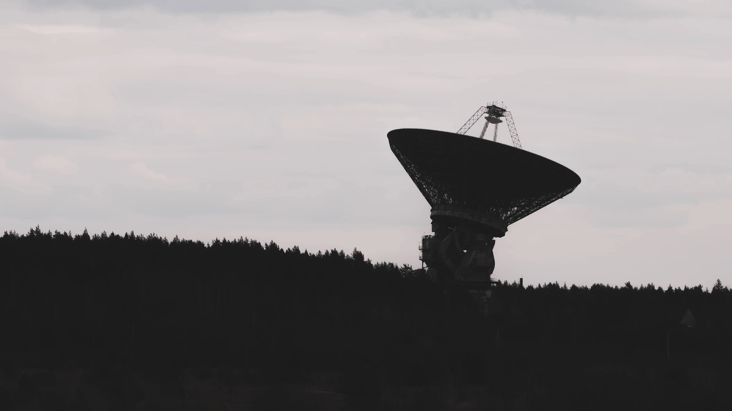 A ground-station dish in silhouette against a dark sky