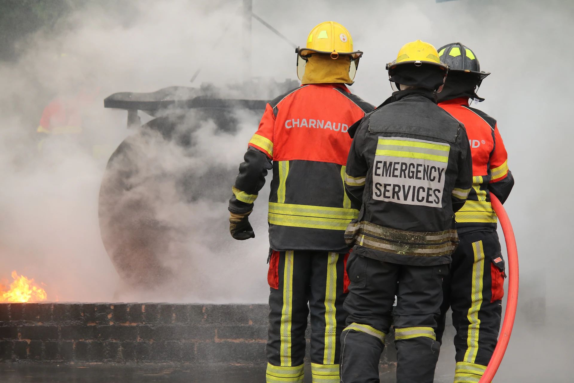 Firefighters stand in front of a burning building.