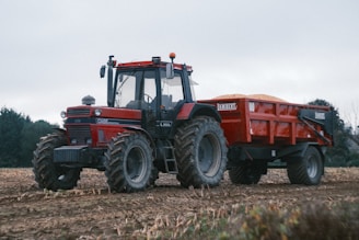 A red tractor pulls a loaded trailer.