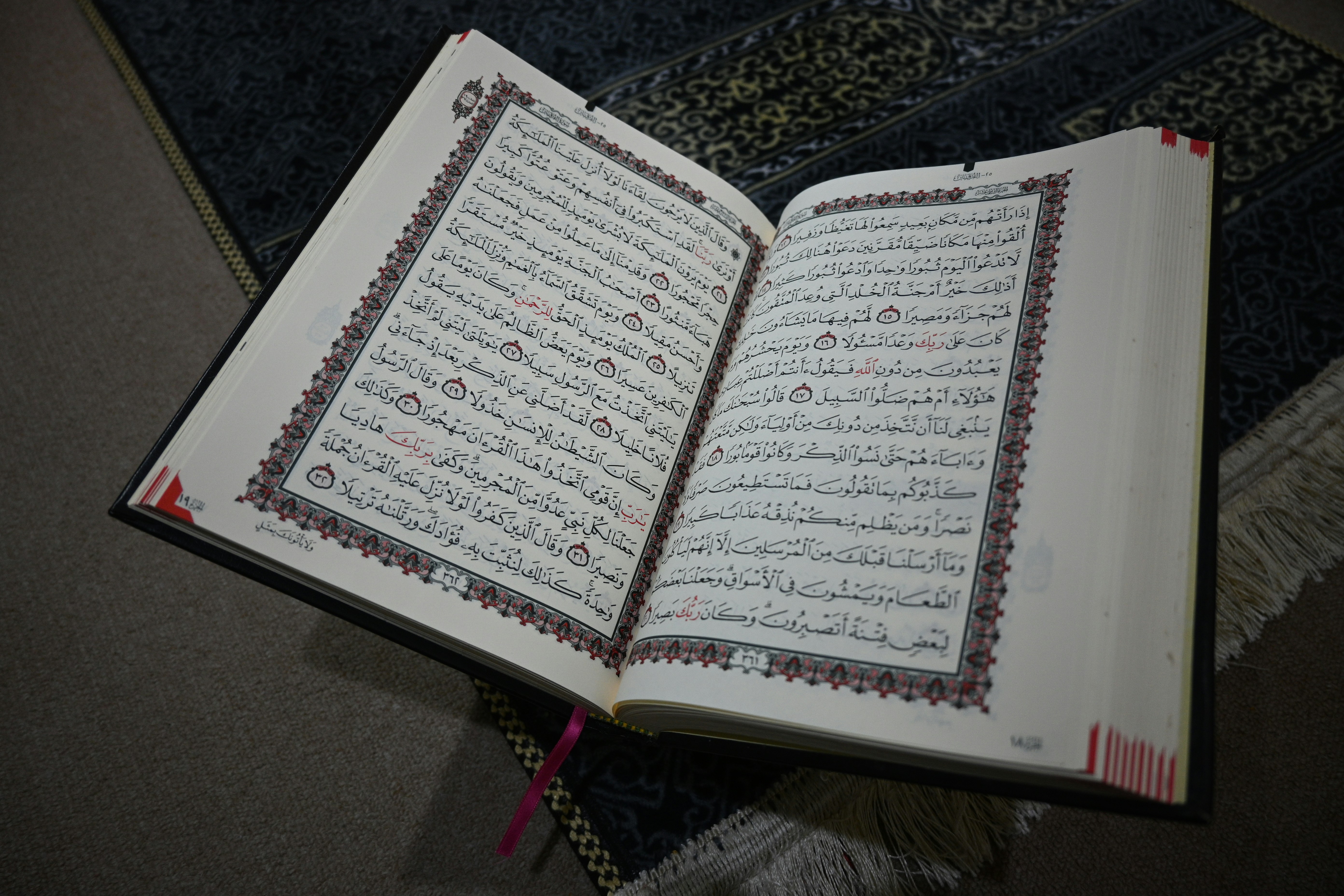 An open quran lies on a prayer mat.