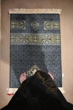 A person kneels on a prayer rug.