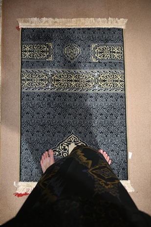 A person kneels on a prayer rug.