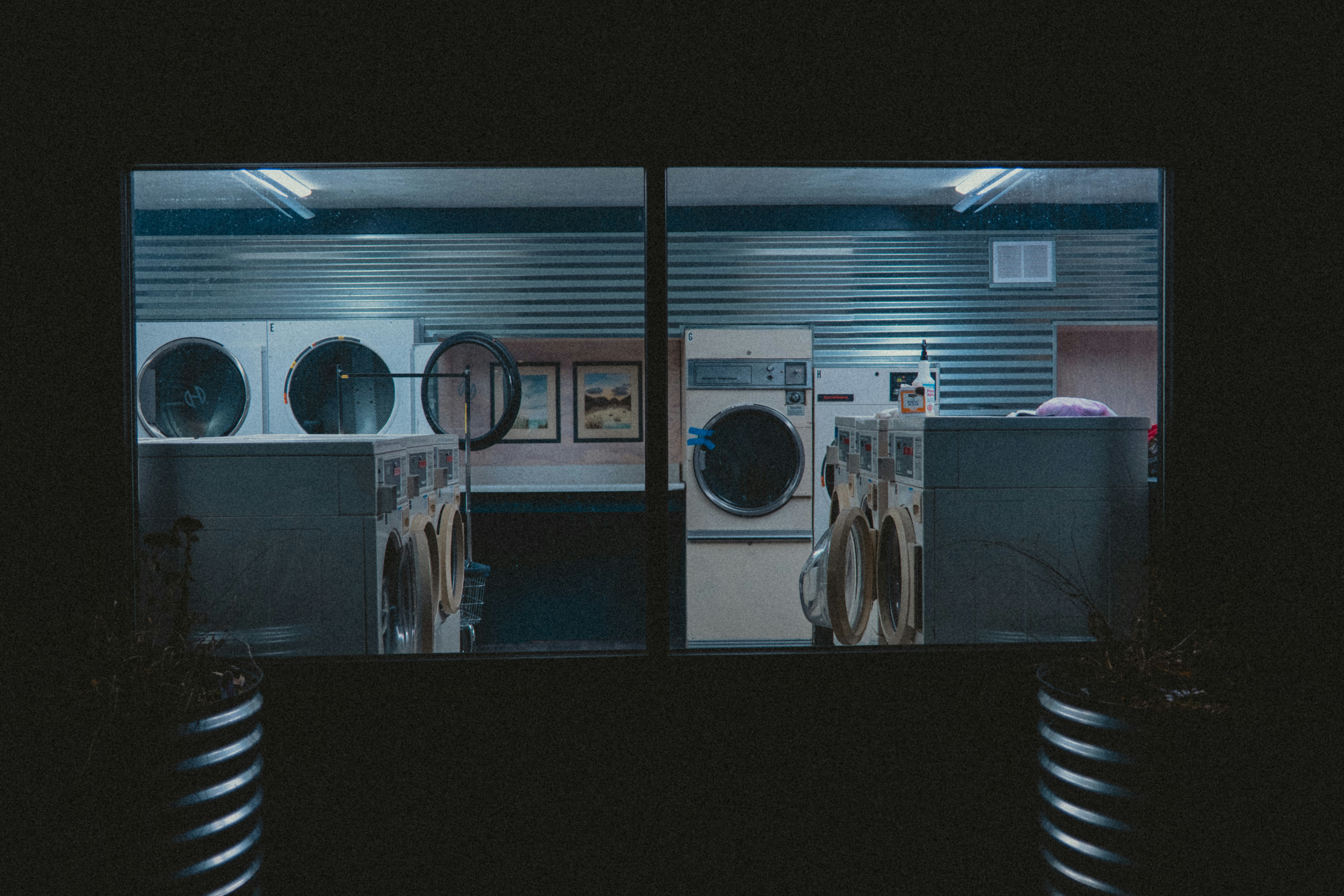 Nighttime view of a laundromat through a window.