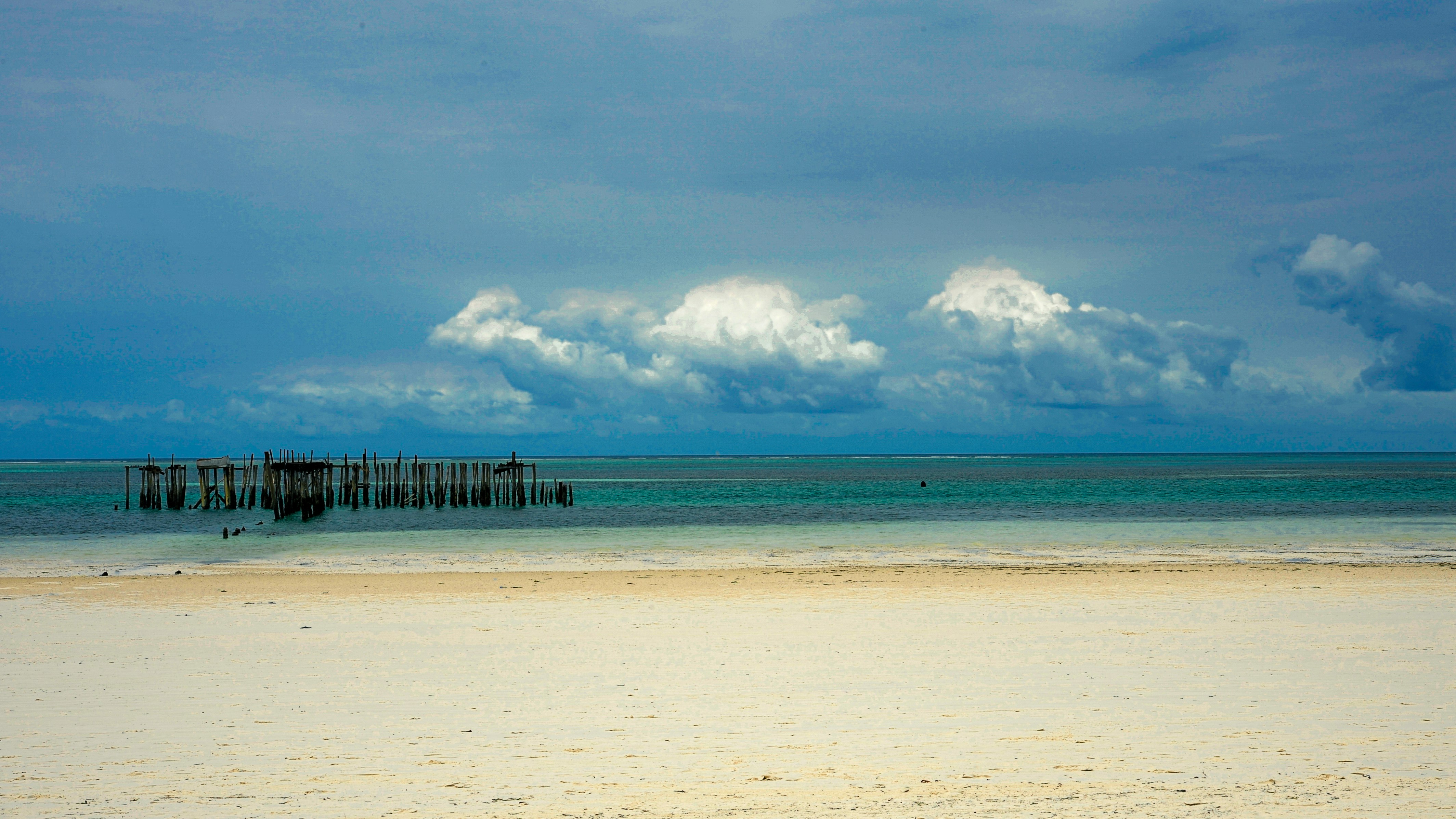 White beach and ocean under a cloudy sky.
