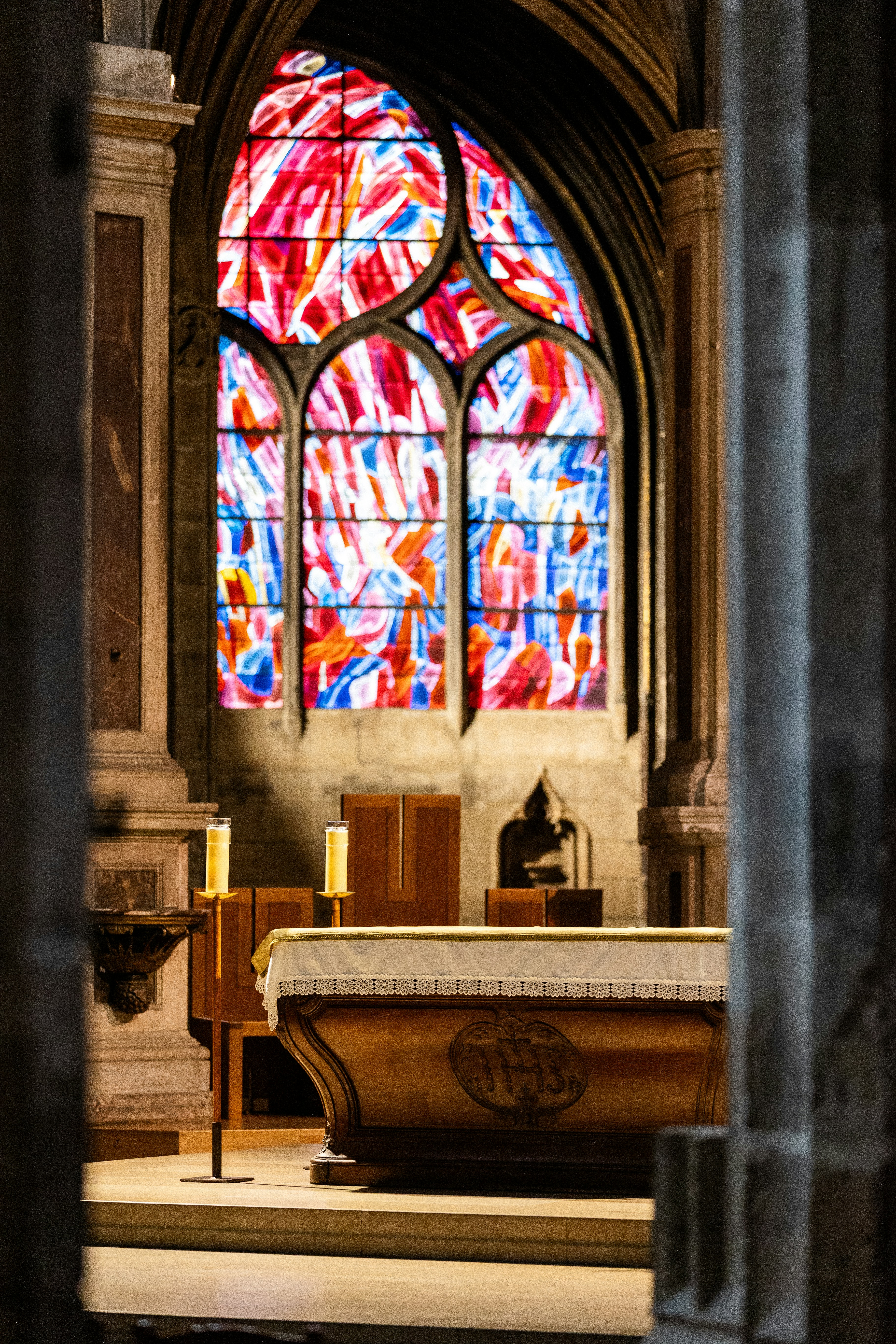 A colorful stained-glass window illuminates a church.