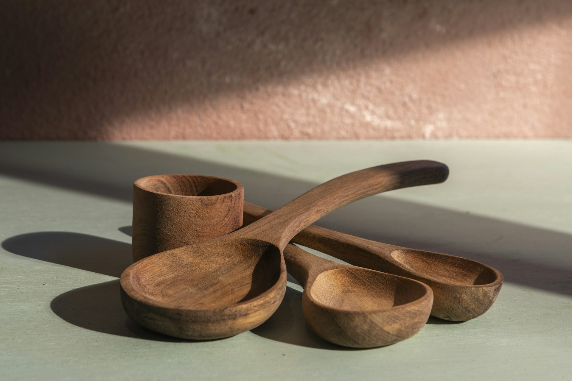 Wooden spoons and a cup sit under light.