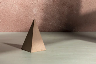 A brown pyramid stands with its strong shadow.