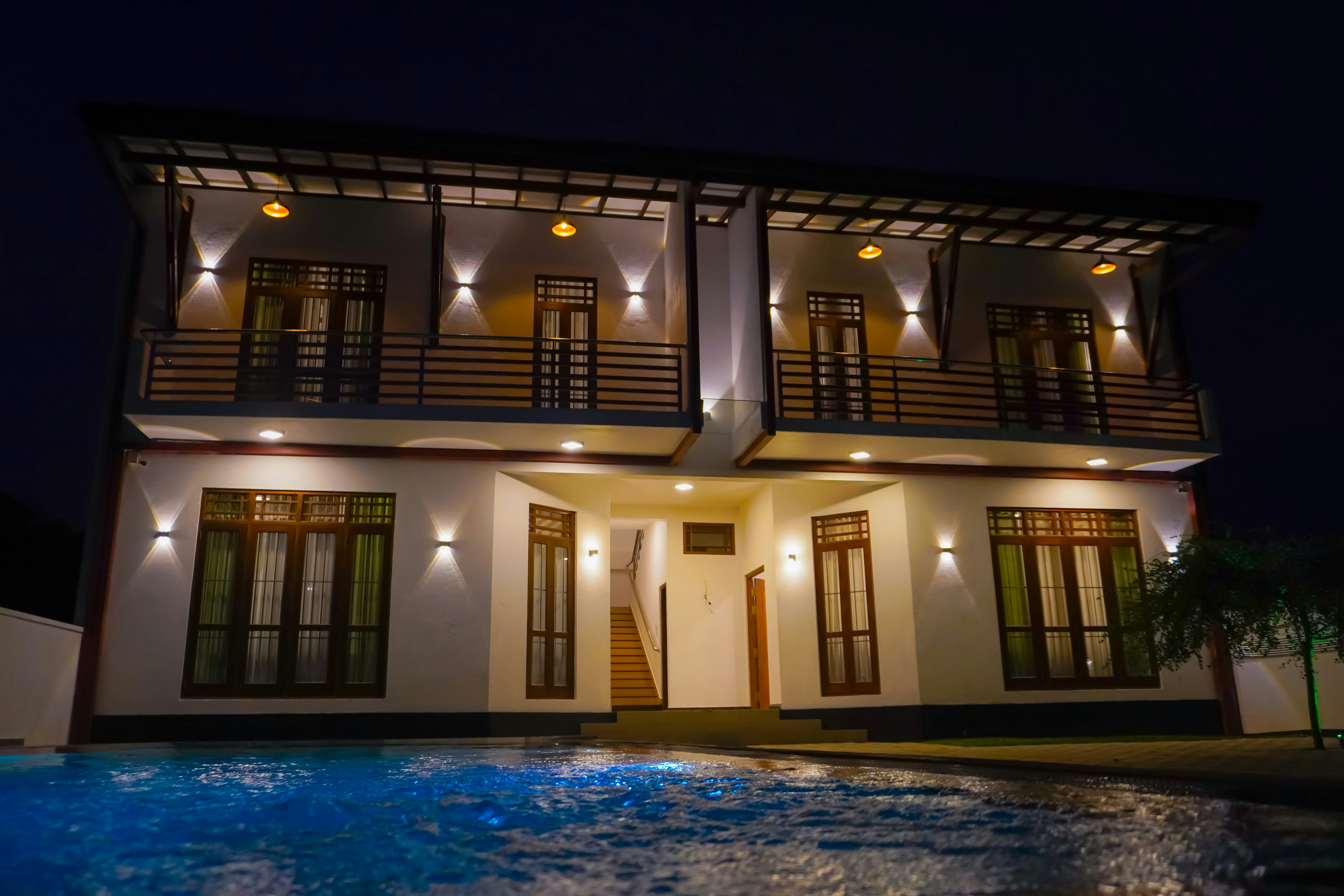 Lit-up modern house with pool at night.