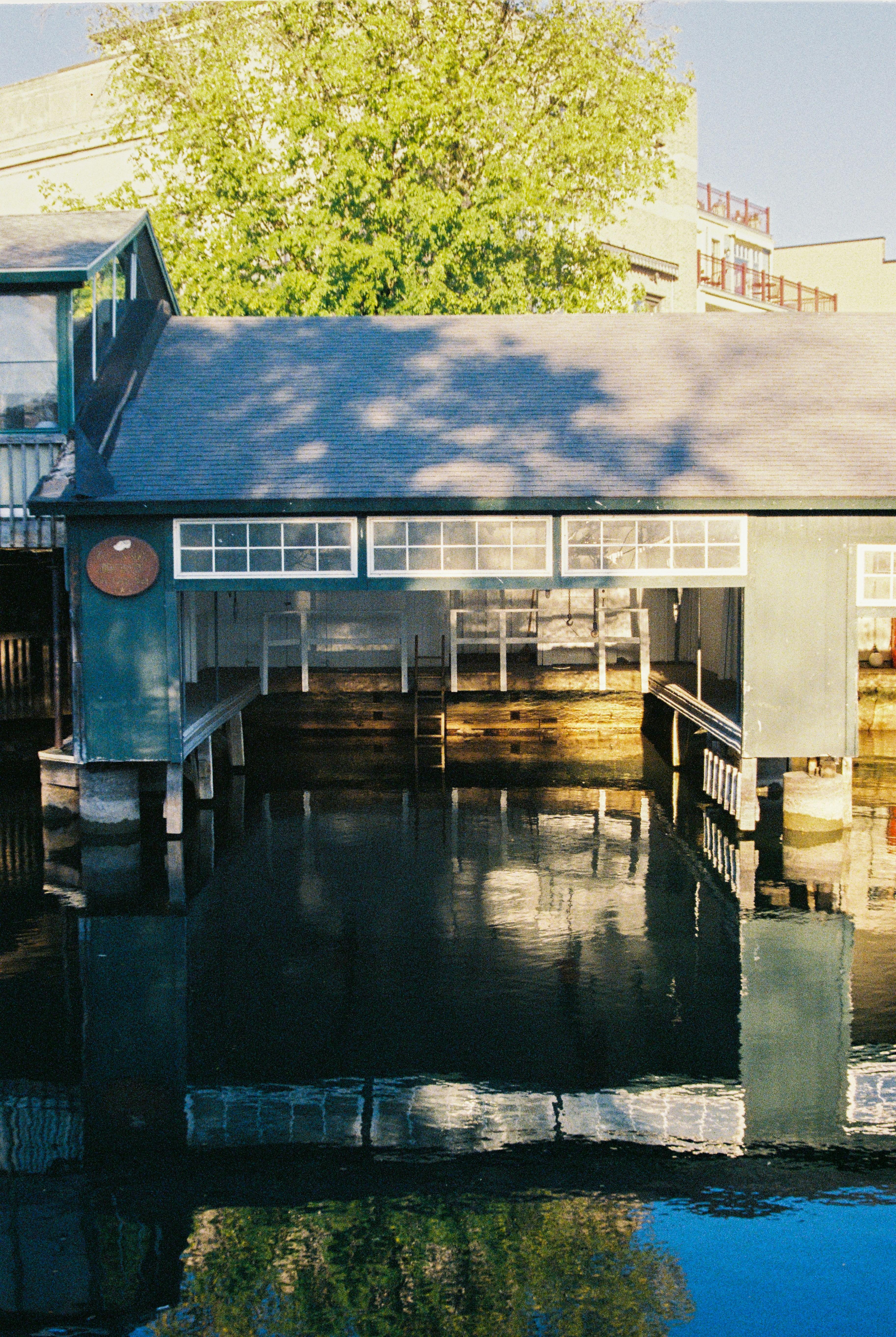 A boat house reflects in still water.