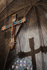 A crucifix hangs inside a church, casting a shadow.