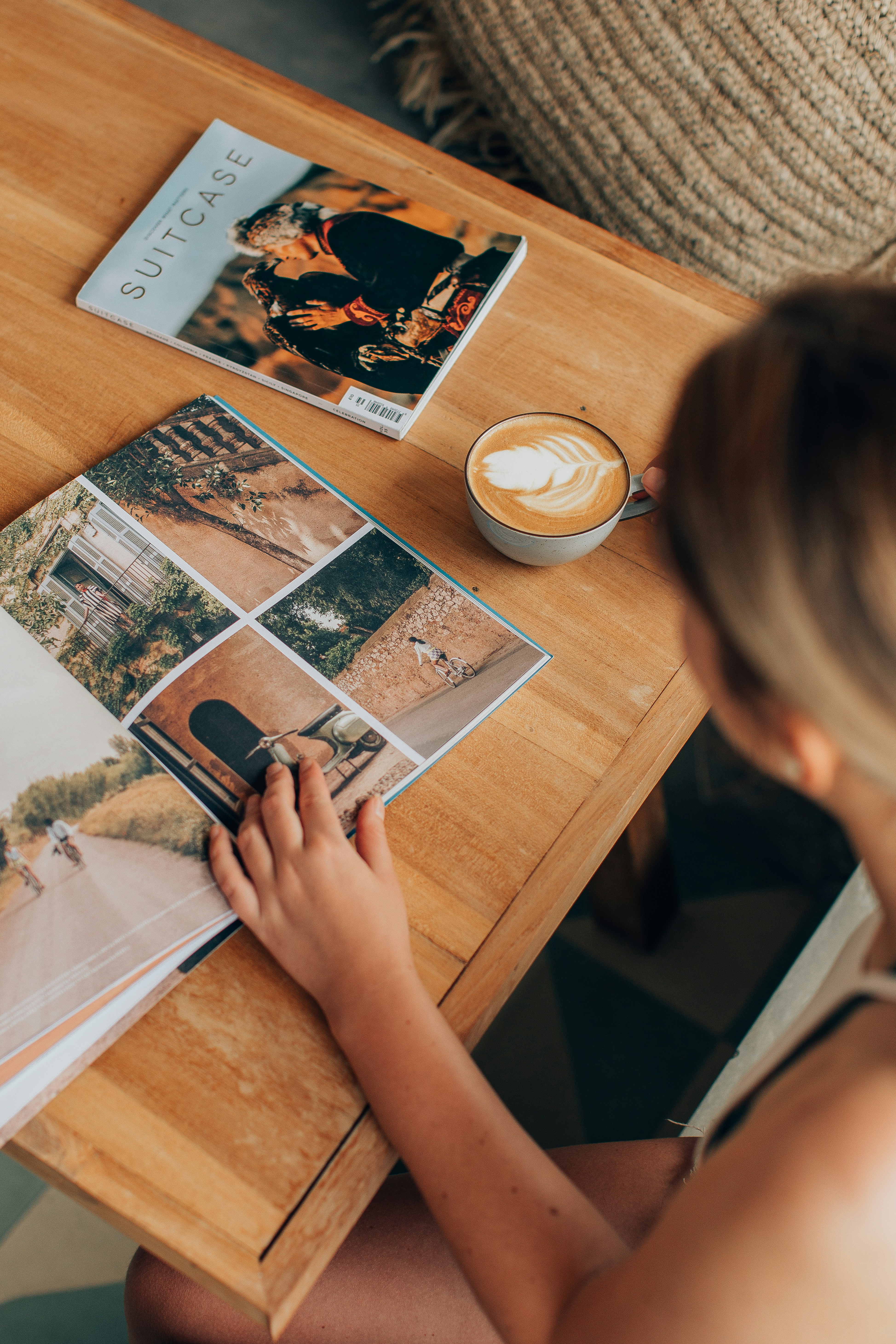 Mulher gosta de café e lê revistas em uma mesa.