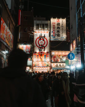 A bustling night scene in a brightly lit asian city.