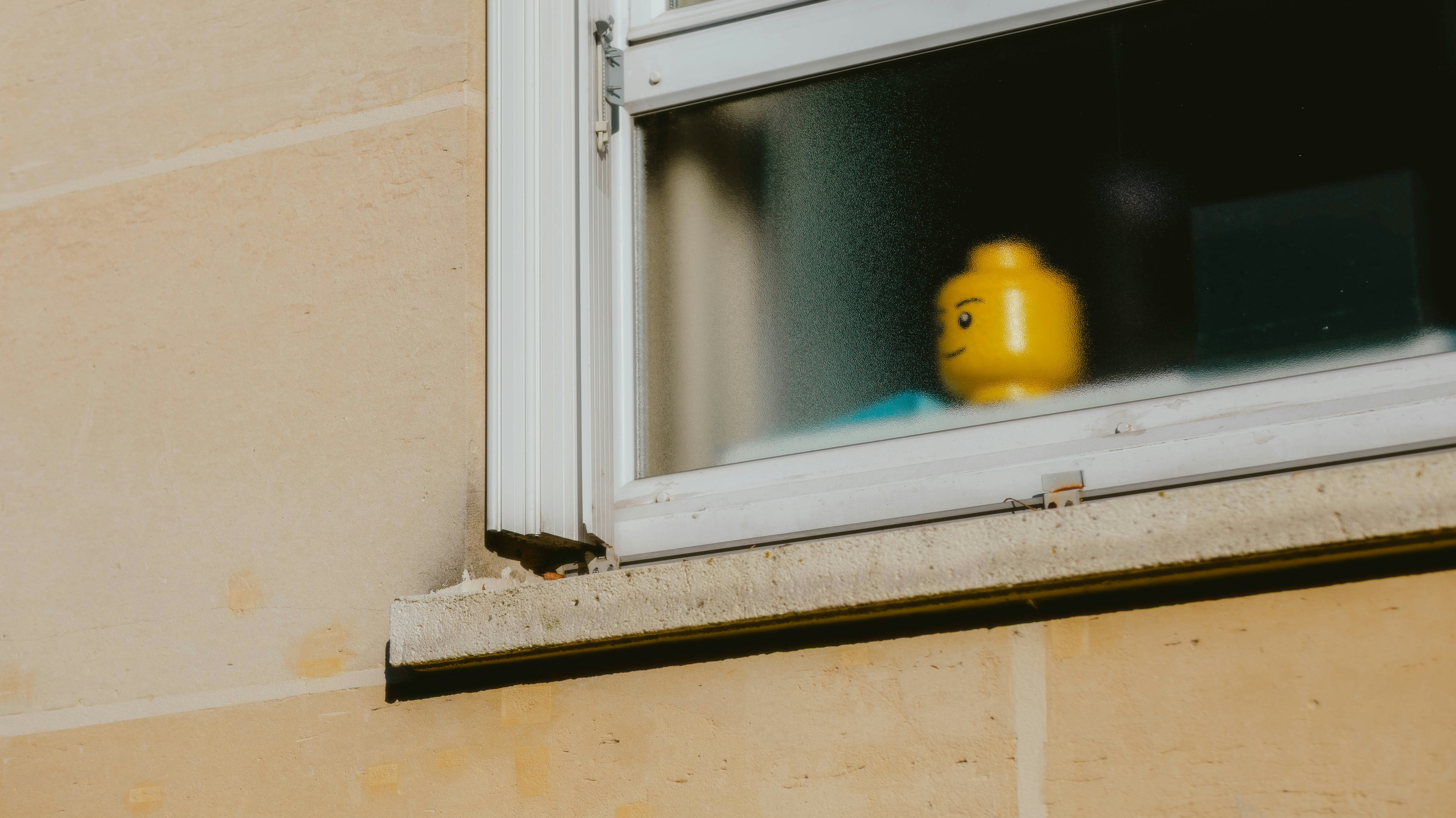 A lego head sits in a window.