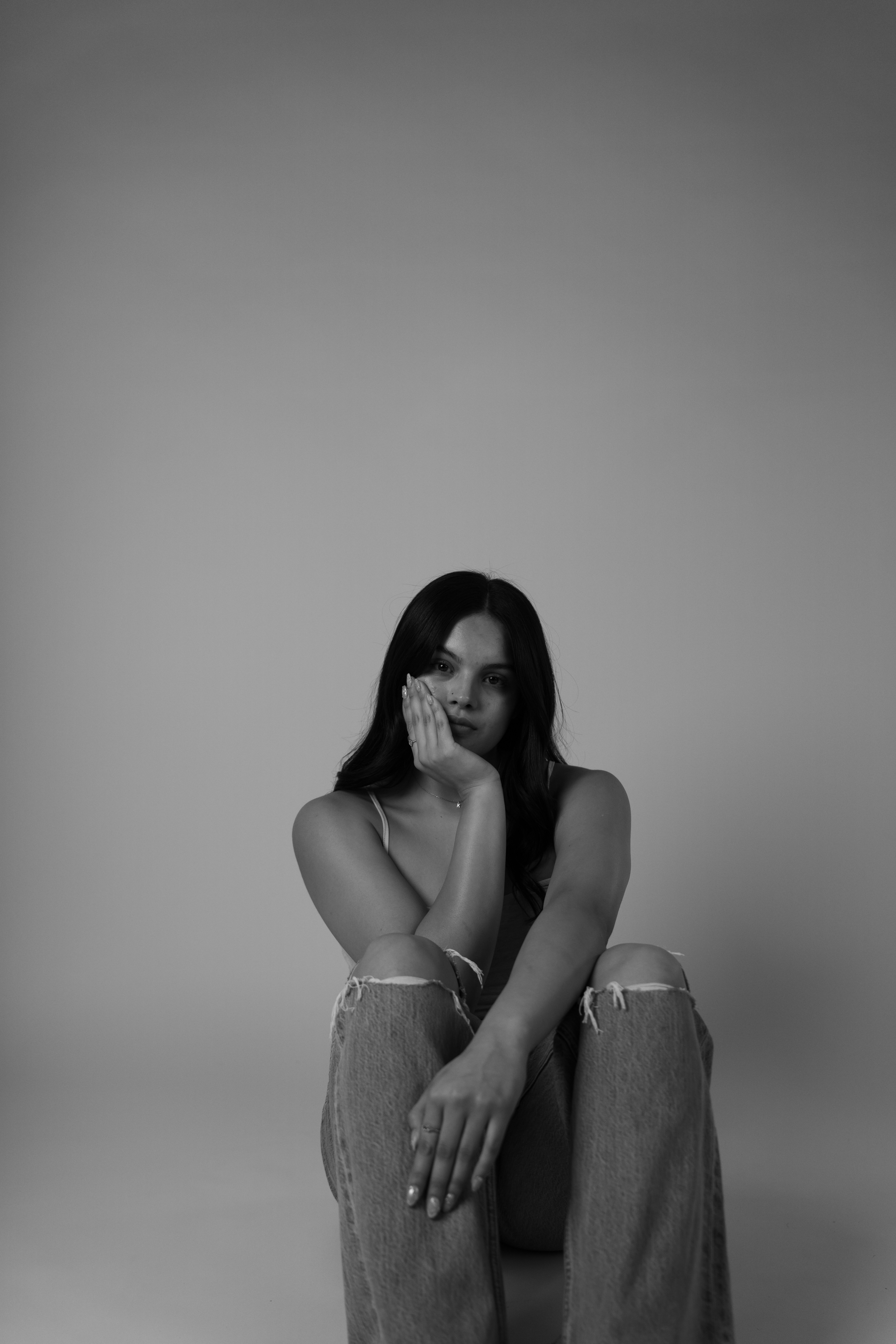 A woman sits sadly in a black and white photo.