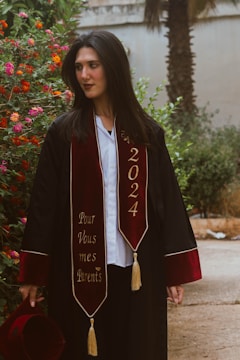 Graduating woman in academic attire looking away.