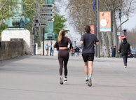 Two people run along a street.