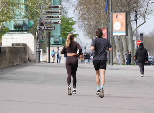 Two people run along a street.