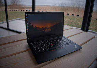 A laptop sits open on a wooden surface.