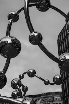 A shiny, modern sculpture reflects the cloudy sky.